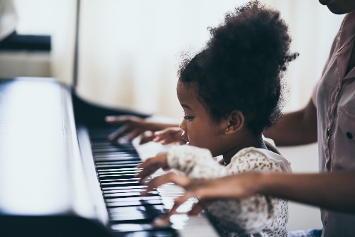 A kid is learning to play the piano in a fun way.