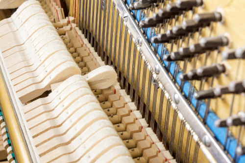 There is a focus on the inside of a piano and a string being struck. 