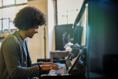 A man plays the piano with a big smile on his face.